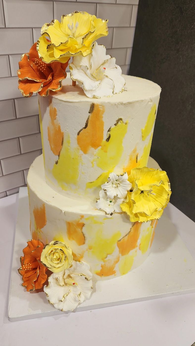 Two-tier yellow and orange watercolor cake with sugar flowers