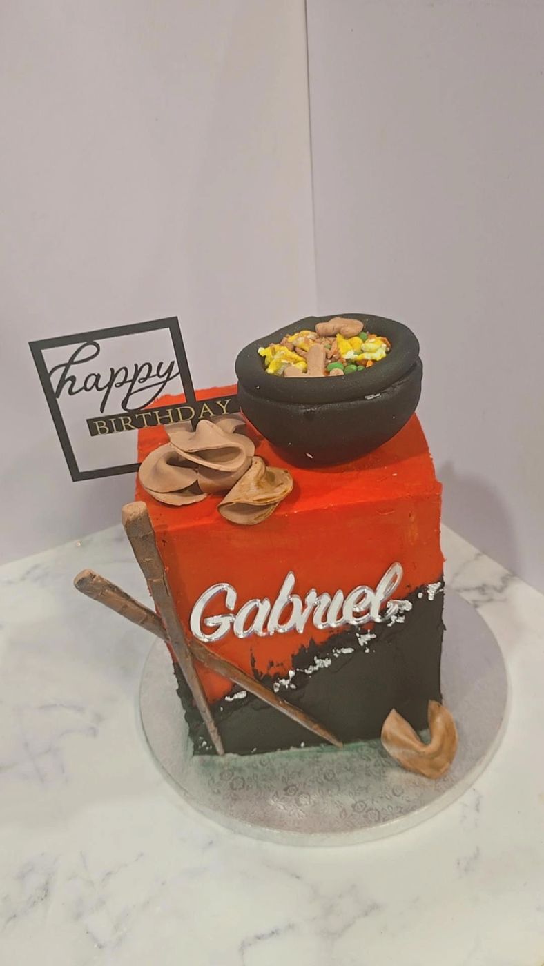 Red and black birthday cake topped with a fondant noodle bowl and fortune cookies