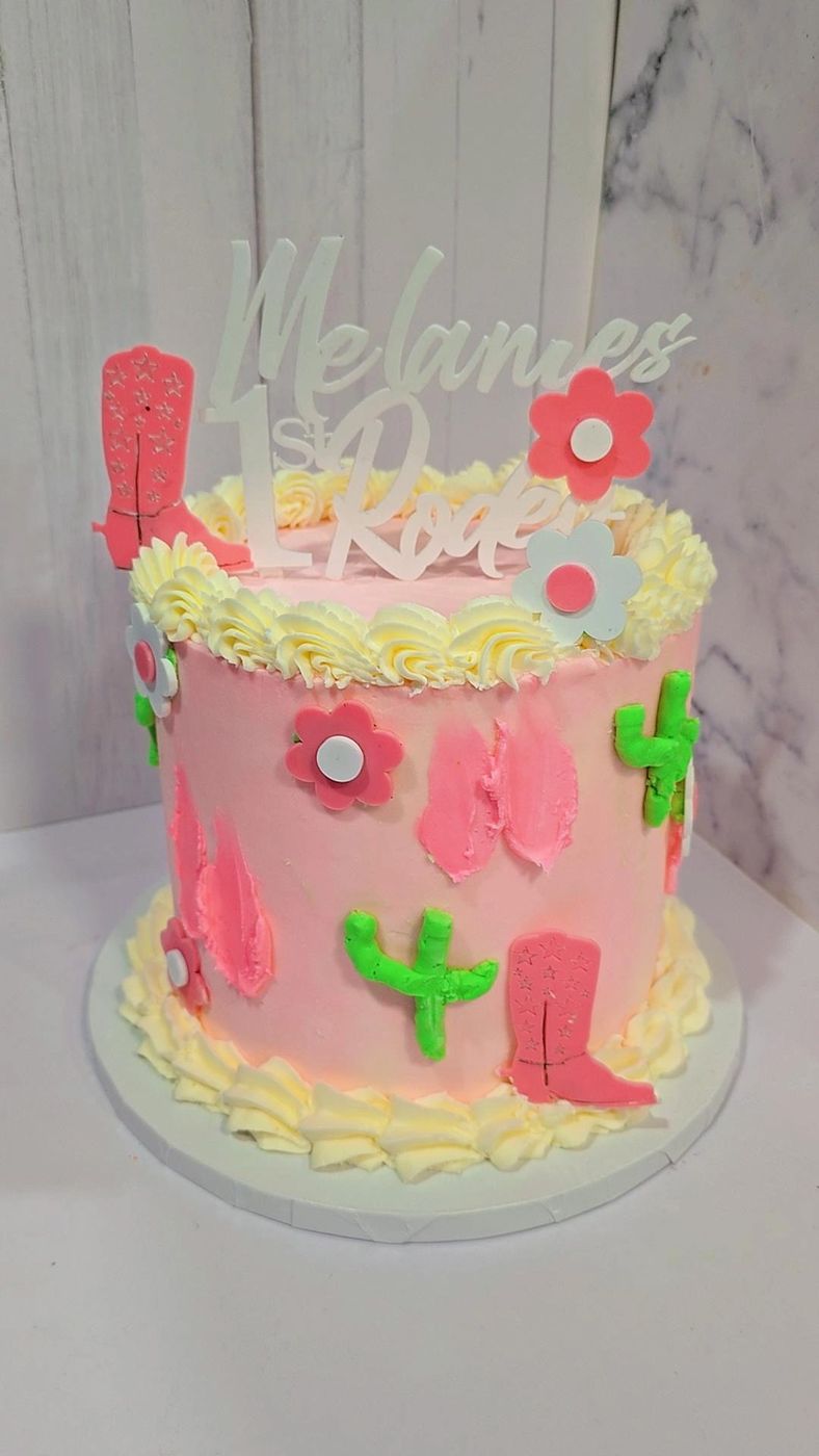 Pink cowgirl-themed cake with cactus, boots and flowers
