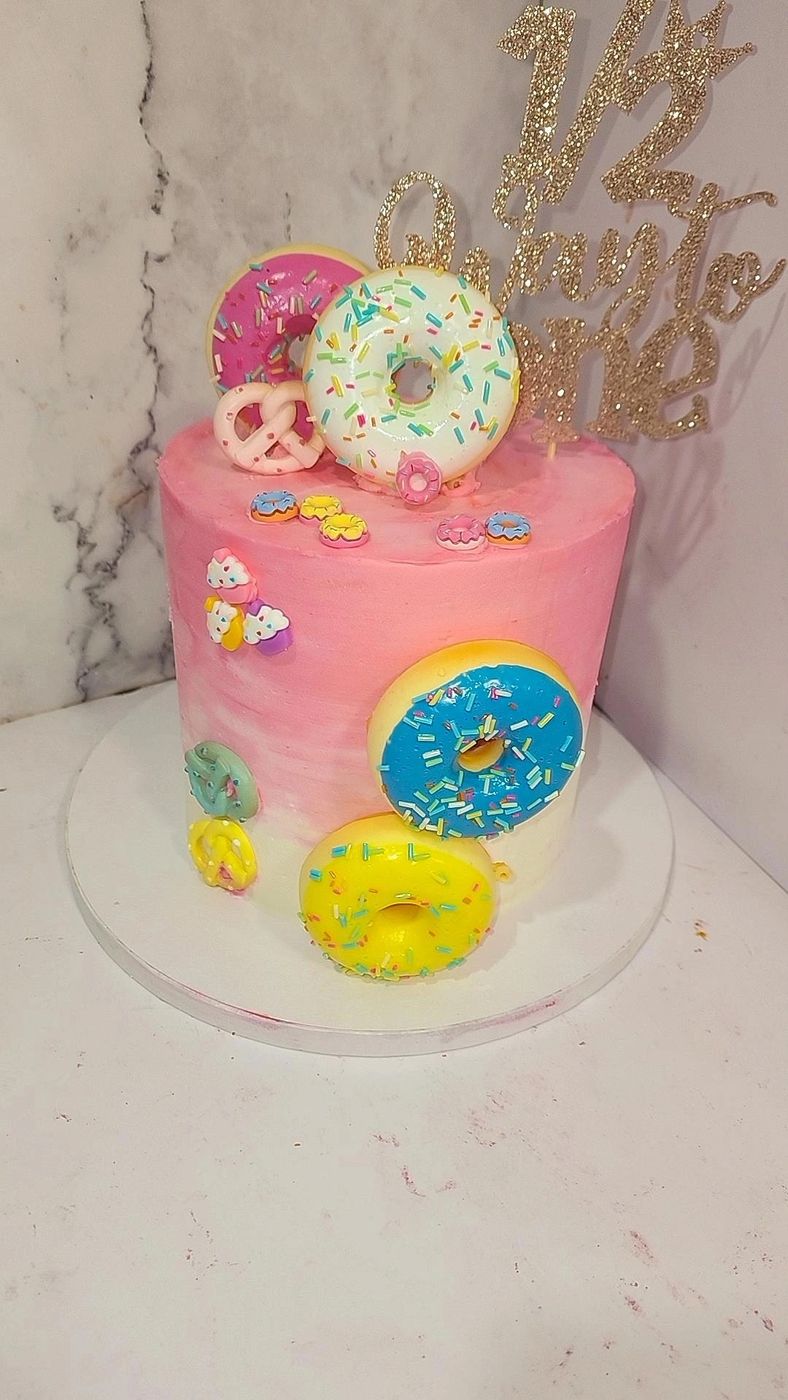 Pink donut-themed cake with sprinkles and a glitter topper