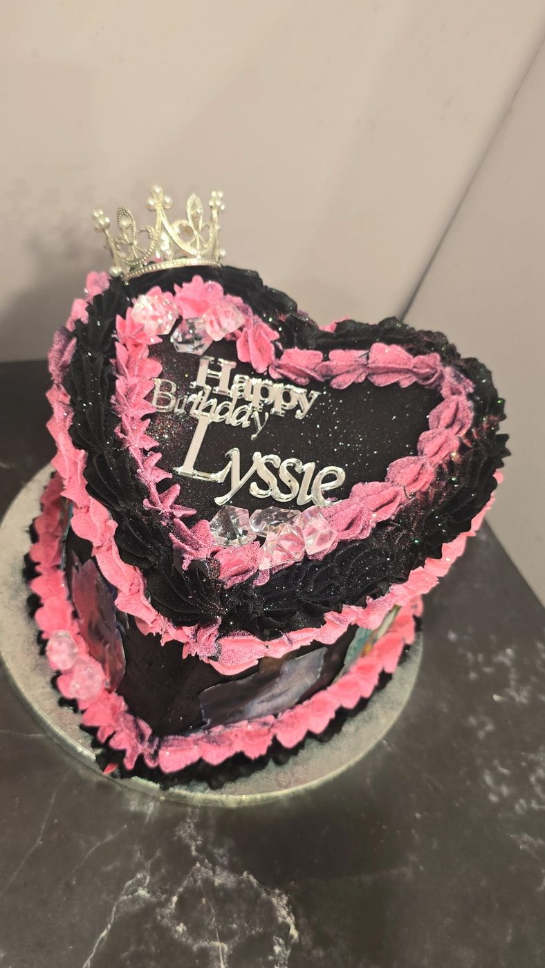 Black and pink heart-shaped cake with a crown topper