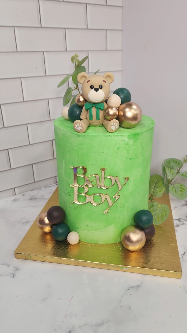 Green baby boy cake with a teddy bear and gold spheres